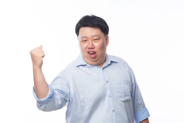 興奮アジアの脂肪男で青シャツで彼の拳を上げ幸せな顔 白の背景に隔離された成功を祝います — ストック写真