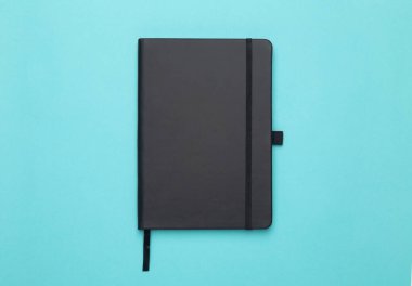 Siyah defter mavi arka planda izole edilmiş. Düz konum veya Üst görünüm açısı.