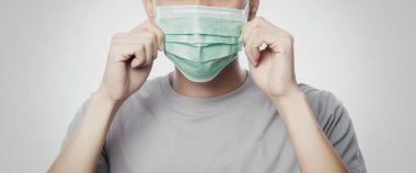 Enfeksiyonu önlemek için hijyenik maske takan genç adam, 2019-nCoV ya da koronavirüs. Öğleden sonra 2.5 gibi hava yoluyla bulaşan solunum hastalığı beyaz arka planda izole edilmiş. Sancak boyutu.