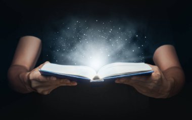 Büyüyen ışıklar ve sihirli tozla adam sihirli bir kitap açtı. Öğrenim ve eğitim kavramı.