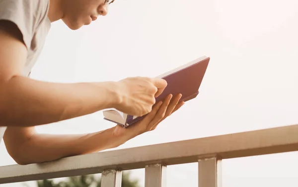 Young man reading book at room balcony in free time from working at home, Knowledge and learning concept.