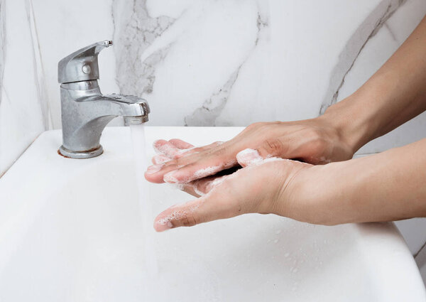 Young man washing hands over sink in bathroom, closeup, Corona virus or Covid-19 prevention, hygiene to stop.