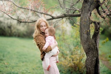 Baharın çiçek açan bahçesinde küçük anne ve bebek