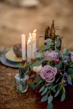 Doğada kırsal tarzda bir düğün masası, cam süsleme, taze çiçekler ve okaliptüs dalları.