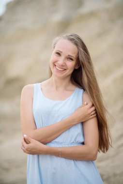 Kumsalda sarı saçlı güzel bir genç kadın.