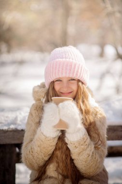 10 yaşındaki tatlı kıvırcık kız ve genç annesi kışın karlı ormanda oynuyorlar.