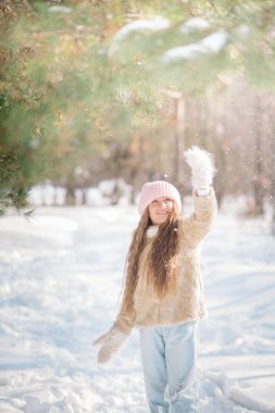 10 yaşındaki tatlı kıvırcık kız kışın karlı bir ormanda oynar.