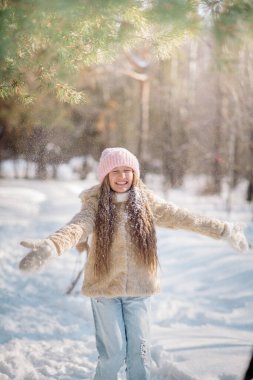 10 yaşındaki tatlı kıvırcık kız kışın karlı bir ormanda oynar.