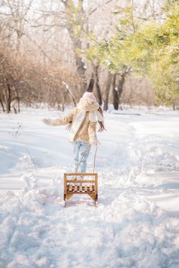 10 yaşındaki tatlı kıvırcık kız kışın karlı bir ormanda oynar.
