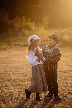 Kız ve oğlan 8 yaşında, tavşanlarla yürüyüşe çıkmış.