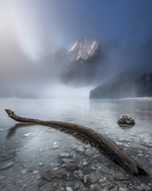 Güney Tyrol, İtalya 'daki Prag Dolomitleri' nde Braies Gölü üzerinde sisli bir gün doğumu. Arka planda Dolomite dağları ve ön planda yüzen eski ahşap direk