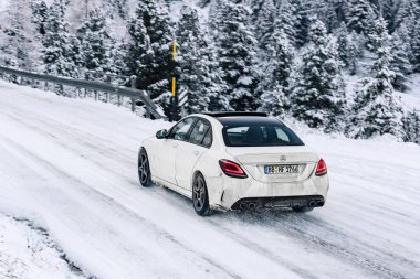 İtalya / Alpler -11,06,2019: Karlı dağ yolunda beyaz Mercedes Benz sedan modeli.