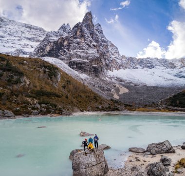 İtalyan Alpleri 'ndeki Sorapis Gölü' nde büyük bir kayanın üzerinde poz veren gezginler.