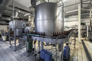 Bira fabrikasındaki taşıma bandındaki kahverengi boş bira şişeleri / kırmızı başlıklı (yüksek Iso görüntüsü))