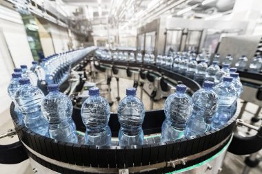 Fabrikada su bulunan plastik şişelerle modern üretim hattı.