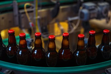 Bira fabrikasında / kırmızı başlıklı (yüksek Iso görüntülü) taşıyıcı banttaki bira şişeleri)