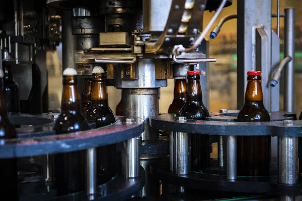 Beer bottles in factory during process of placing caps on top (high ISO image)