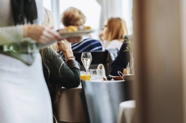 Lokantadaki masada bir bardak şarap ve ön planda bulanık bir memur..