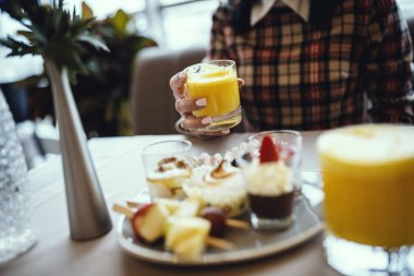 Sıradan giyinmiş kadınlar restoranda taze portakal suyu içiyor..