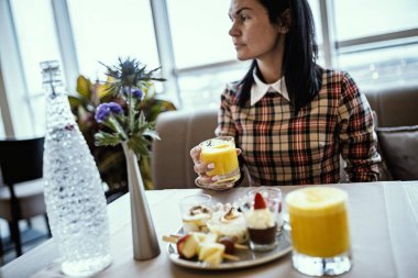 Sıradan giyinmiş kadınlar restoranda taze portakal suyu içiyor..