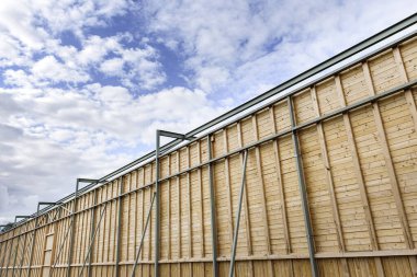 Açık havada metal parçaları olan uzun tahta bir duvar..