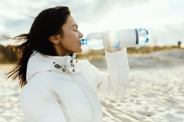 Deniz manzaralı plastik su şişesi tutan ve içen kadınlar 