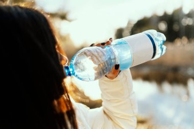 Deniz manzaralı plastik su şişesi tutan ve içen kadınlar 