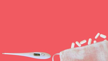 Tıbbi bileşim. Coronavirus koruma düzlüğü, yüz maskesi ve elektronik termometrenin altındaki tabletlerin pembe arka planda yüksek sıcaklıkta izole edilmiş görüntüsüydü. Metnin ya da tasarımın için şablon