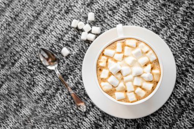 Gri arka planda şekerleme olan bir fincan kahve. Kupa 'nın yanında çay kaşığı var.