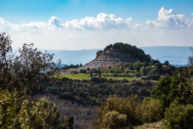 Orman ve küçük köyle çevrili bir tepe.