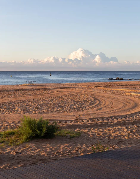 Mattinata tranquilla sulla spiaggia vuota con impronte di pneumatici su sabbia, mare e nuvole sullo sfondo — Foto Stock