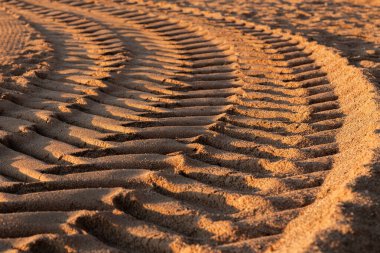 Gün boyunca kumda araba lastiği izleri, seçici odaklanma.