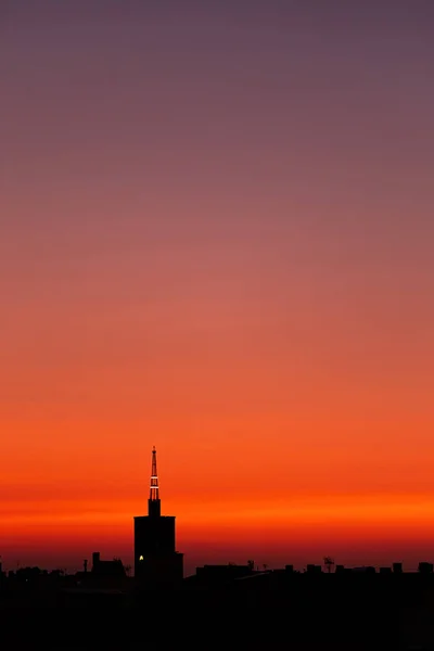 紫红的夏日日出，屋顶俯瞰着城市上方一座古老的教堂塔. — 图库照片