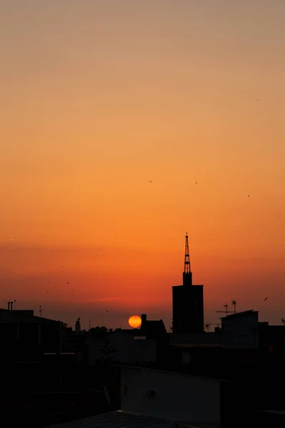 Оранжевый летний рассвет, вид на крышу старой церковной башни над городом . — стоковое фото