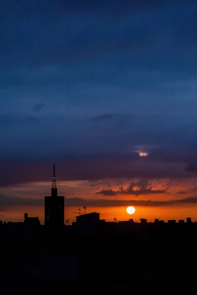 太阳升起在城市上空，俯瞰着一座古老的教堂塔. — 图库照片