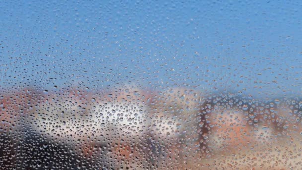 Vetro appannato di finestra con texture gocce d'acqua e edifici sfocati sullo sfondo . — Video Stock