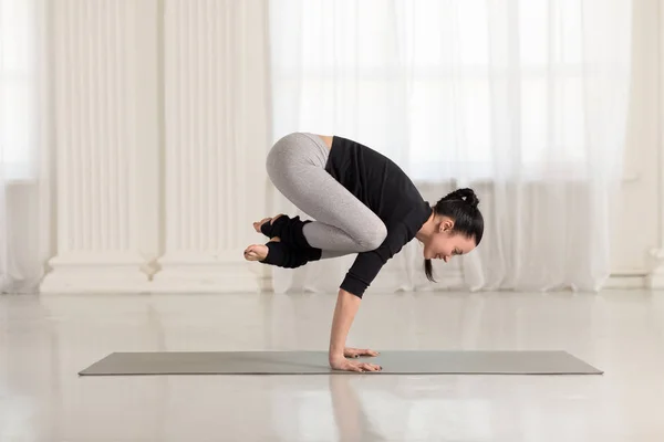 Vacker ung asiatisk kvinna tränar inomhus, gör yoga motion på grå matta, handstand asana, träning för armar och handleder styrka, Crane Crow Pose, Bakasana — Stockfoto