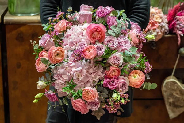 Florista detém belo buquê de rosas mistas e outras flores em uma loja. Flores frescas cortadas — Fotografia de Stock