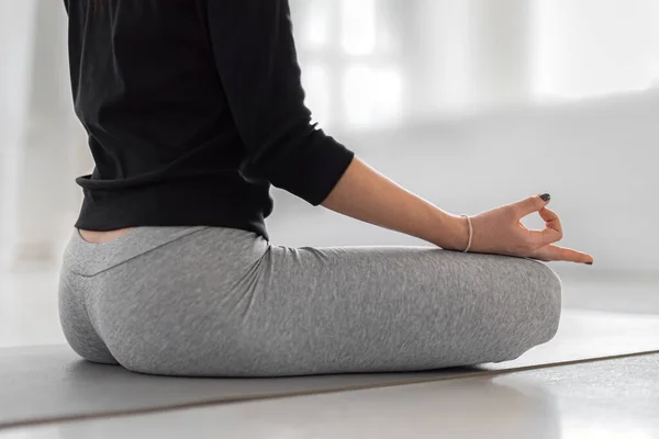 Meditation medan du gör lotus pose. En kvinna sitter på grå matta och utövar yoga i klassen. Root Chakra Pose med båda fingrarna — Stockfoto