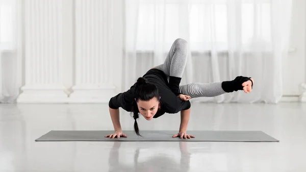 Ung asiatisk attraktiv kvinna utövar yoga, stående i Dragonfly pose. Sport i vita hallen. — Stockfoto