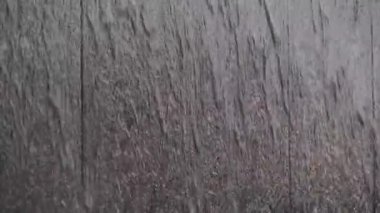 Şehirde şiddetli yağmur. Su siyah taş duvar boyunca akar..