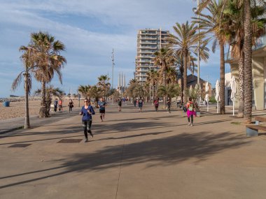 BADALONA, İspanya - Mayıs 02 2020: Koronavirüs karantinasının ilk gününde insanlar gezinti güvertesi boyunca koşu yapıyorlar 