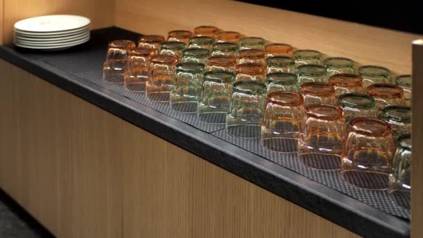 Sideboard baru nebo restaurace s průhlednými sklenicemi na pití vody nebo džusu a bílých talířů