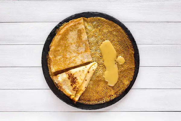 Crêpes Blini und Honig auf weißem Holzhintergrund, Draufsicht. Hausgemachte dünne Pfannkuchen zum Frühstück oder Dessert. — Stockfoto