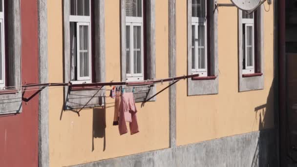 İpte asılı kıyafetleri kurutmak, rüzgarda çırpınmak. Porto, Portekiz ve Avrupa 'daki eski binaların dış yüzeyi. — Stok video