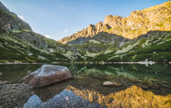 Horské jezero s rockem v popředí při západu slunce — Stock fotografie