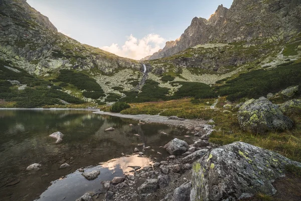 Horské jezero s kameny v popředí při západu slunce — Stock fotografie