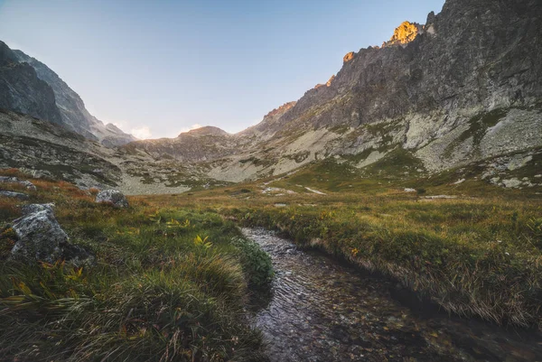 Potok v údolí pod vrcholky hor při západu slunce — Stock fotografie
