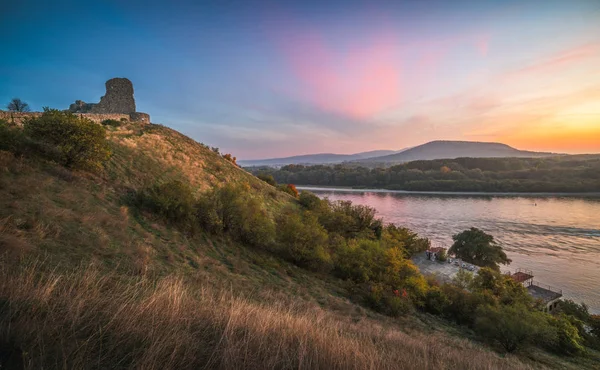 Ruína em uma colina sobre um rio ao pôr do sol — Fotografia de Stock