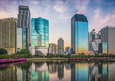 Alacakaranlık 'taki bir gölde yansıtılan gökdelenler. Bangkok, Tayland 'daki Benjakiti Parkı